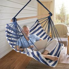 a man sitting in a blue and white striped hammock using a laptop computer