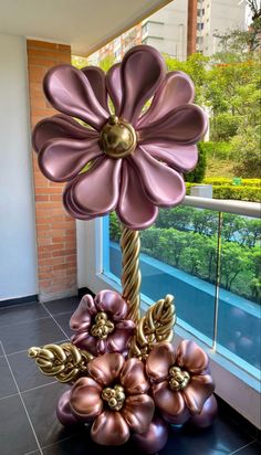 a large metal flower sculpture sitting on top of a black tile floor next to a window