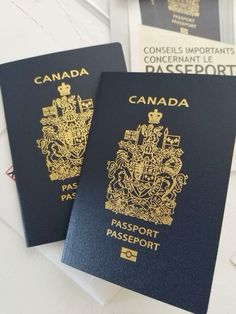 two canadian passports sitting next to each other on top of a white table with papers