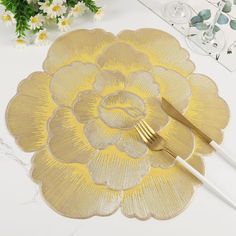 a gold flower place mat with two forks