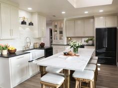 a kitchen with white cabinets and counter tops, black appliances and an island in the middle