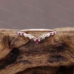 a silver ring with red stones on top of a piece of driftwood in front of a brown background