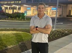 a man standing on the sidewalk with his arms crossed in front of an office building