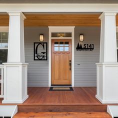 the front porch of a house with wood floors and white pillars on either side of it