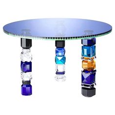 a round glass table with four different colored vases on it