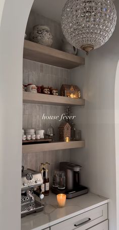 a kitchen with open shelving and chandelier hanging from the ceiling above it