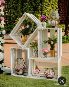 a white shelf filled with flowers and potted plants on top of it's sides