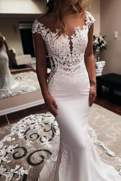 a woman in a white wedding dress standing on a rug with her reflection in the mirror