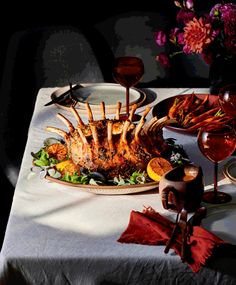 a table topped with a turkey covered in sauces and garnished with orange slices