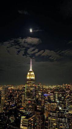 the empire building is lit up at night in new york city, with full moon