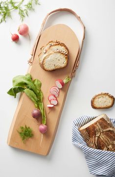 a cutting board with bread, radishes and lettuce next to it