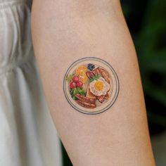 a person with a plate of food tattooed on their left arm and the other side of her arm