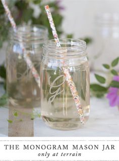 two mason jars with straws and flowers in the background