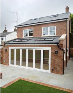 a brick house with white doors and windows on the outside, surrounded by green grass