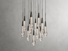 a bunch of light bulbs hanging from the ceiling in front of a gray wall and floor