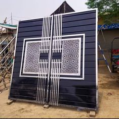 a blue building with an intricate design on it's side in the middle of a dirt area