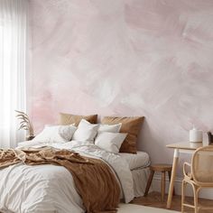 a bedroom with pink paint on the wall and white bedding in front of it