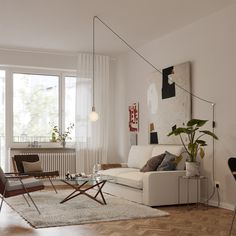 a living room filled with furniture and a large window covered in white curtained curtains