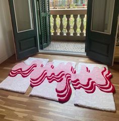 two rugs on the floor in front of an open door with red and white designs