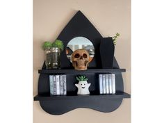 there is a shelf with books and a skull head on the top, along with other items