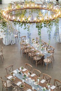 the tables are set up with place settings and flowers hanging from the chandelier