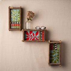 three wooden boxes with colorful designs on them and one has a vase filled with flowers