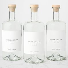 three bottles of water sitting on top of a white countertop next to each other