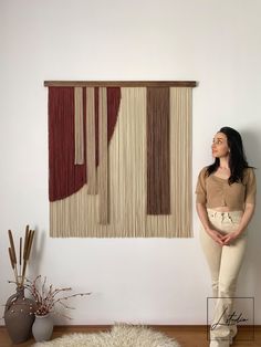 a woman standing in front of a wall hanging