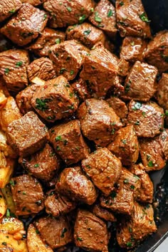 meat and potatoes in a skillet with parsley on the side, ready to be eaten