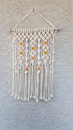 a white wall hanging on the side of a building with beads and tassels