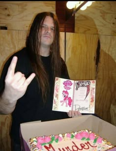 a man with long hair holding up a birthday cake