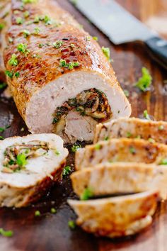 sliced up meat on a cutting board next to a knife and some parsley sprigs