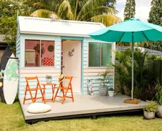 a small blue house with two orange chairs and an umbrella on the deck in front of it