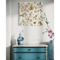 a blue dresser with flowers on it and a painting hanging above the top that has shells on it