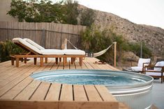 a hot tub sitting on top of a wooden deck next to a hammock