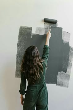 a woman is painting the wall with gray paint