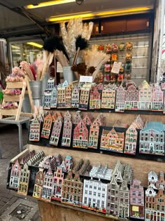 a display case filled with lots of miniature buildings and flowers in front of a store