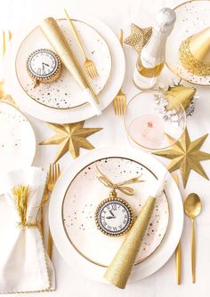 the table is set with gold and white plates, napkins, and silverware