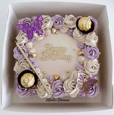 a birthday cake in a box decorated with purple and gold decorations