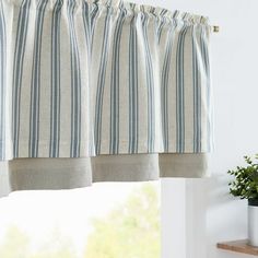 a kitchen window with blue and white striped curtains hanging from it's valance