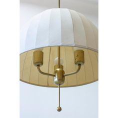 a white and gold lamp shade hanging from a ceiling fixture with two lights on each side