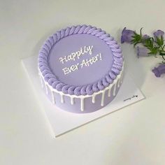 a purple birthday cake with white icing and flowers