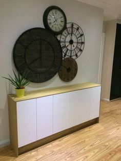 there are clocks mounted on the wall in this living room, and two planters