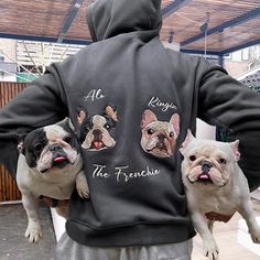 a man holding two dogs in his arms while wearing a jacket with french bulldogs on it