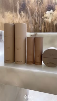 four different types of skin care products sitting on a counter next to some dry grass