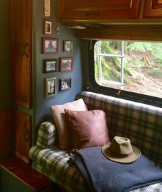 a couch with a hat on it in front of a window that has pictures on the wall