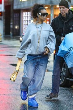 the woman is walking down the street with an umbrella in her hand and wearing blue boots