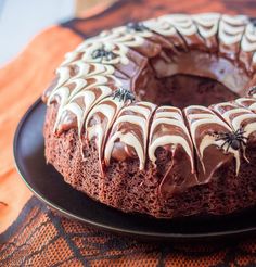 a chocolate bundt cake with white frosting and spider web decorations on the top