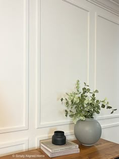 a vase with some flowers on top of a wooden table next to a book shelf