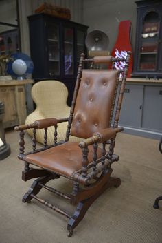 a brown leather rocking chair sitting on top of a carpeted floor